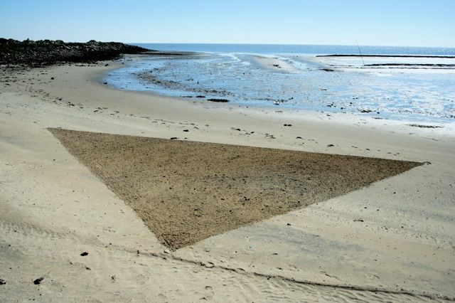 Drawing a triangle on the beach using a stick. Color changed by weather